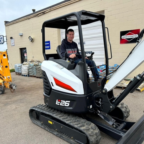 Boyne Co-Op Hardware and Rental staff on top of a mini excavator